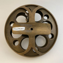 A brass side-mount reel. Large holes are cut through the sides to allow air circulation to help dry the silk lines used at the time.
