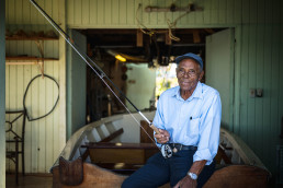 Ansil Saunders sitting on a boat, holding a fishing rod and reel.