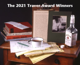 Items once belonging to John Voelker, AKA Robert Traver, including books, a notepad, manuscript pages, a green pen, and a tin cup.