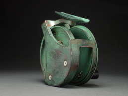 A handmade copper-green fishing reel.