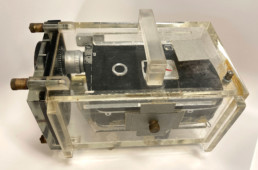 A 1950s video camera inside a hard, clear, sealed plastic case with handles.