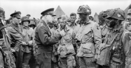 Dwight Eisenhower speaks to troops in the field, and appears to be demonstrating how to cast a fly rod.