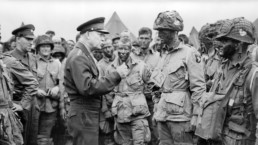 Dwight Eisenhower speaks to troops in the field, and appears to be demonstrating how to cast a fly rod.