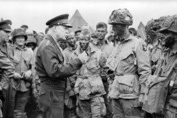 Dwight Eisenhower speaks to troops in the field, and appears to be demonstrating how to cast a fly rod.