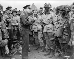 Dwight Eisenhower speaks to troops in the field, and appears to be demonstrating how to cast a fly rod.