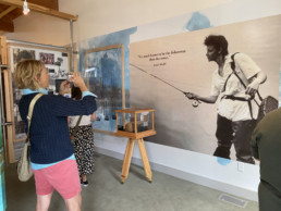 A visitor takes a picture of a large photo of Joan Wulff that dominates one wall of the exhibition. On the photo is a quote by Joan: 