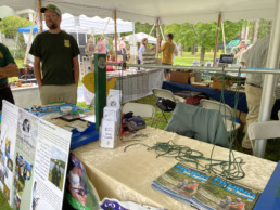 The Vermont Fish and Wildlife table featured a long metal pole between 2-3 foot tall wooden struts. Lengths of green rope are draped over the pole for teaching how to tie knots.