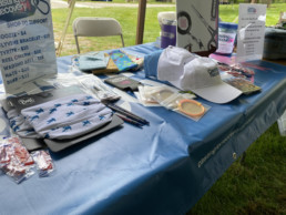 The Casting for Recovery table with various items for sale, including hats, wading belts, doozies, and neck gaiters.