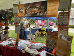 The Native Fish Coalition of Vermont's table features goods for sale, informational posters, and a large banner with the words 