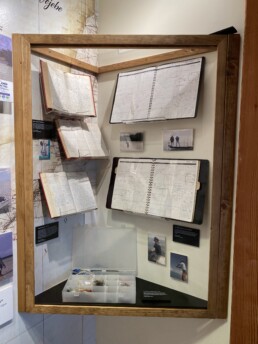 A display case in the Jose Wejebe exhibit featuring some of his log books and journals, as well as a number of flies in a storage box.