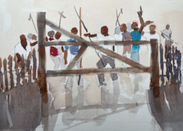 A group of black men are lined up along the other side of a closed wooden gate. Some are holding objects, while others are gesturing.