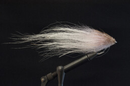 Long saltwater streamer made of bucktail hair. The tail is white, shading toward pink by the bend of the hook and becoming brown at the eye of the hook. The hair around the eye is clipped close, giving the head of the fly a bullet-like profile.