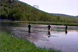 A video screenshot of three anglers standing in a shallow stream.